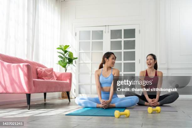 attractive two young woman doing yoga stretching yoga in the living room at home. - colchoneta de ejercicio fotografías e imágenes de stock