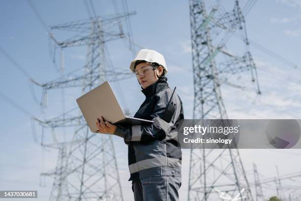 electrical engineer is overhauling high-voltage wires - hochspannungsmast stock-fotos und bilder