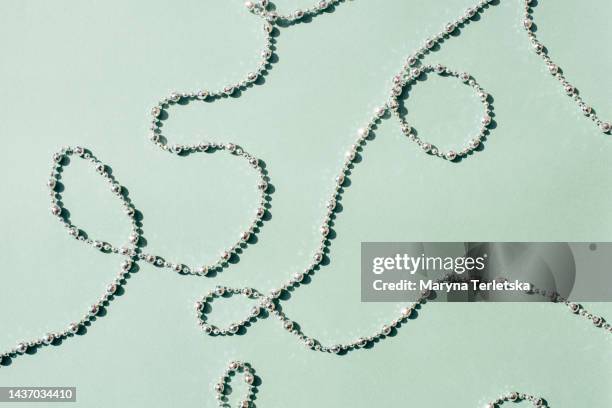 silver and gold beads on a green background. universal holiday background. - bead string stock pictures, royalty-free photos & images