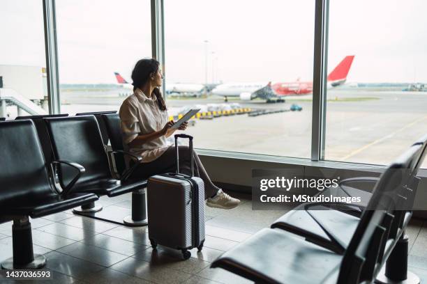 young female passenger waiting for flight at airport lounge - luchthaventerminal stockfoto's en -beelden