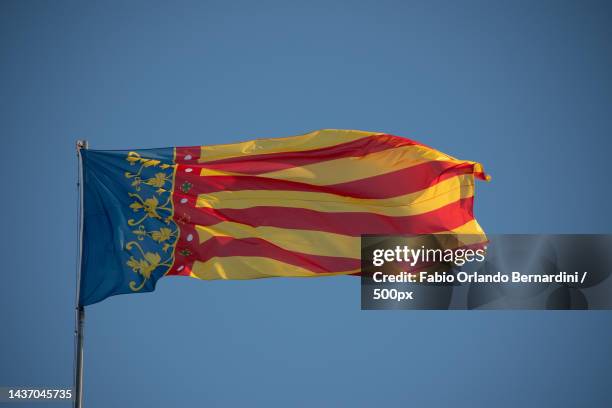 low angle view of flag against clear blue sky,valencia,comunidad valenciana,spain - giallo stock pictures, royalty-free photos & images