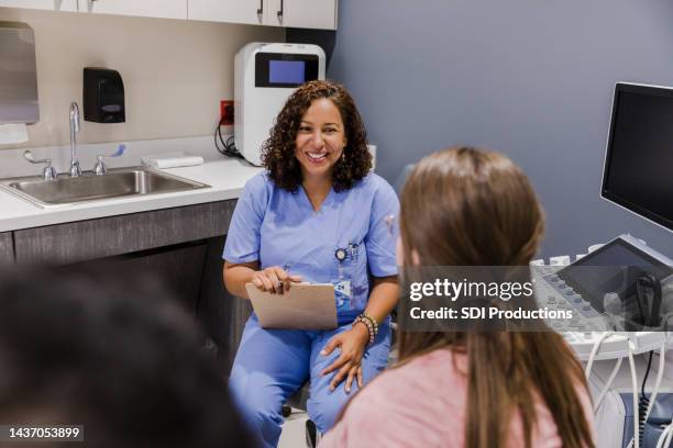 weiblicher ultraschalltechniker lächelt unkenntliches paar an - obgyn stock-fotos und bilder
