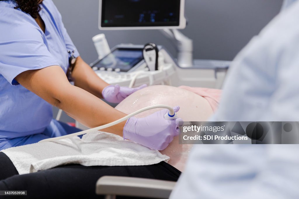 Unrecognizable female technician performs ultrasound on unrecognizable pregnant woman