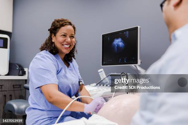 tech sonríe a papá mientras le hace ultrasonido a su esposa - ecografista fotografías e imágenes de stock