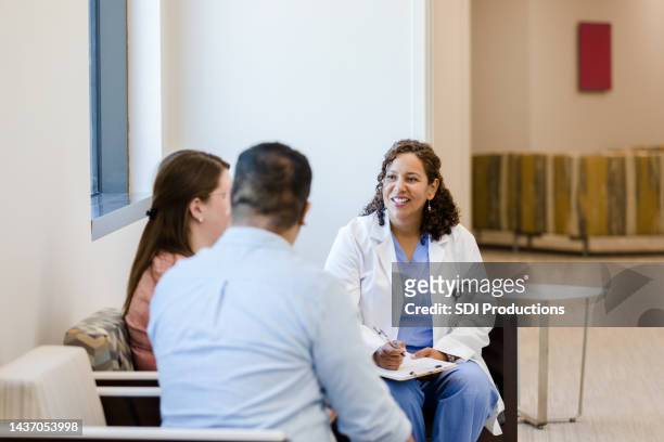 female patient shares as husband and ob/gyn listen - married doctor stock pictures, royalty-free photos & images