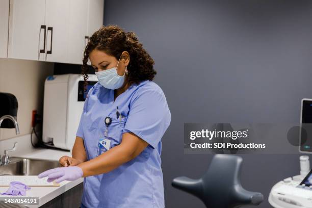 nurse preparing herself for the next patient - protective glove stock pictures, royalty-free photos & images