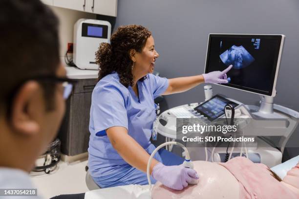 l'ecografista femminile indica lo schermo del computer - obstetrician foto e immagini stock