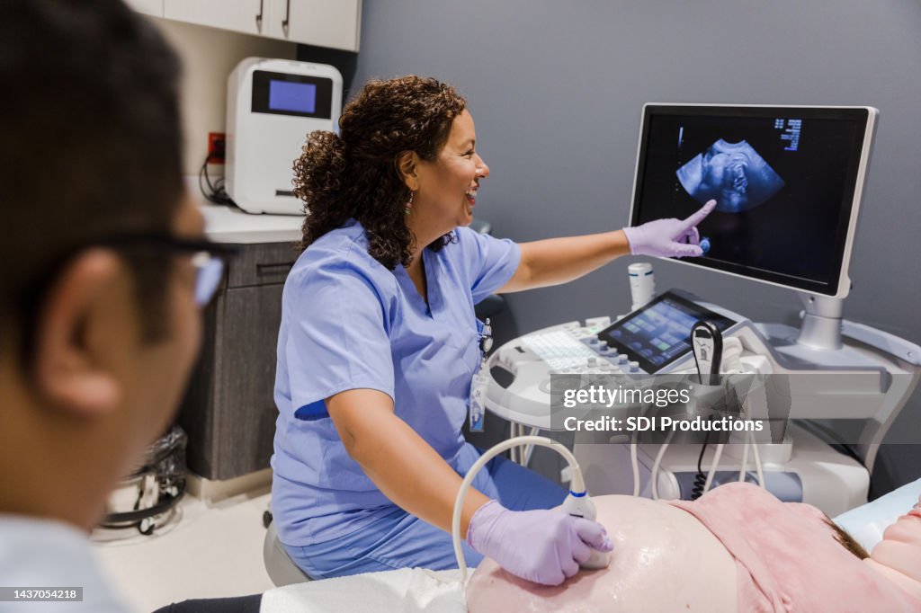 Female sonographer points to the computer screen