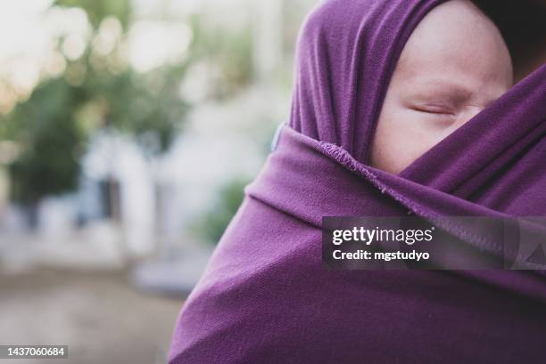 nahaufnahme schlafendes baby in einem tragetuch - schleppe kleidung stock-fotos und bilder