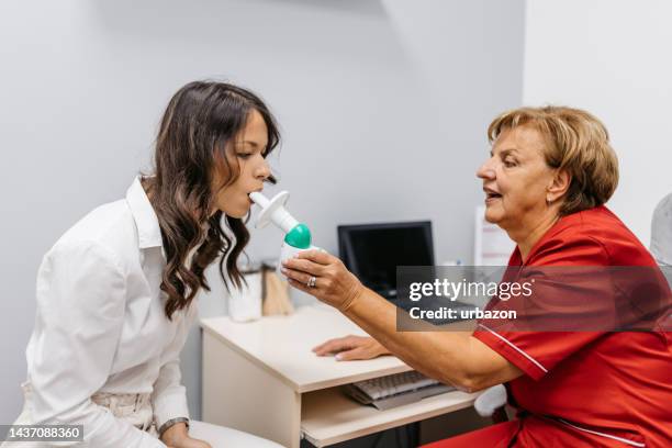 mujer joven tomando una prueba de espirometría en una clínica médica - aliento fotografías e imágenes de stock