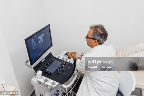 young woman having a thyroid gland exam in a medical clinic - thyroid exam stock pictures, royalty-free photos & images