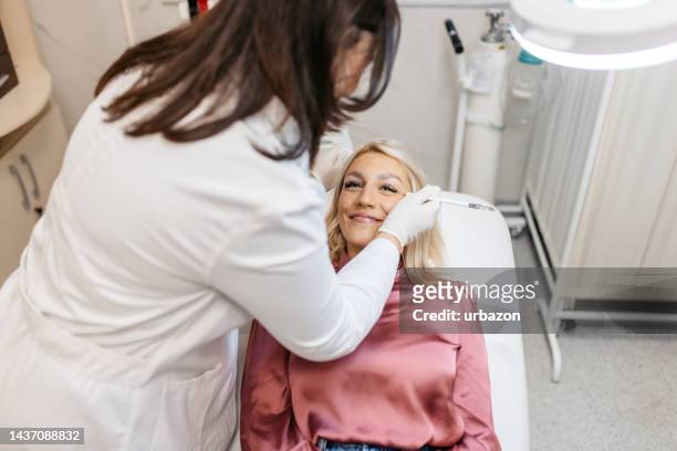 junge frau bekommt botox-injektionen in einer medizinischen klinik - kosmetikerin stock-fotos und bilder