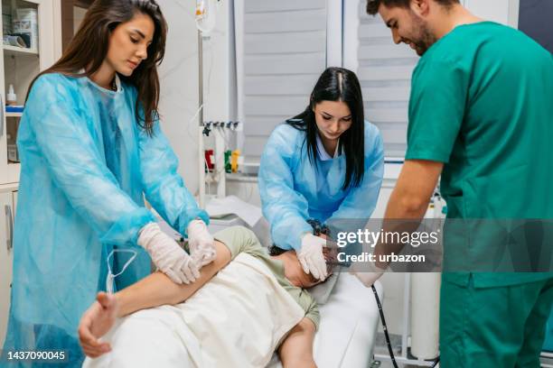 team of hospital staff performing gastroscopy on a male patient - endoscope stock pictures, royalty-free photos & images