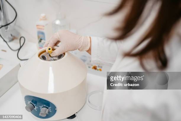 female doctor putting blood samples in a centrifuge machine - hematology 個照片及圖片檔