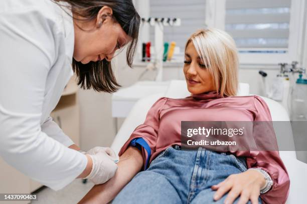 médico tomando muestras de sangre de una paciente femenina - blood donation fotografías e imágenes de stock