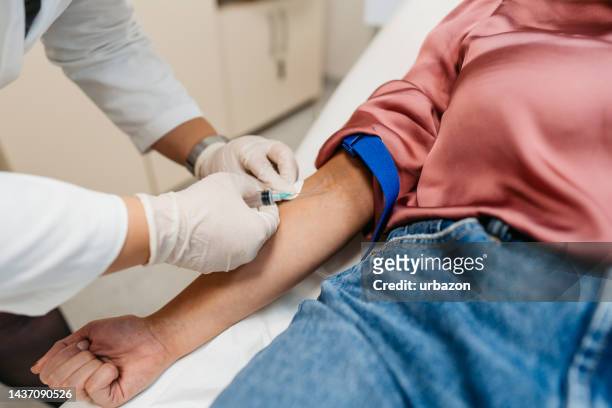 doctor taking blood samples from a female patient - removal men stockfoto's en -beelden