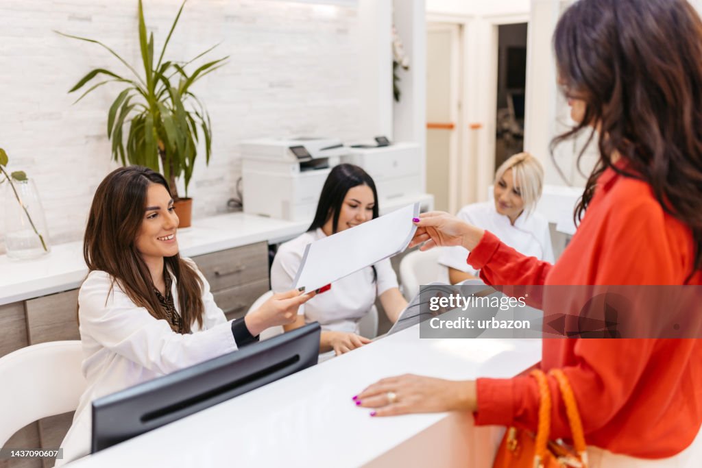 Female Patient Giving Her Documents To The Hospital Receptionist