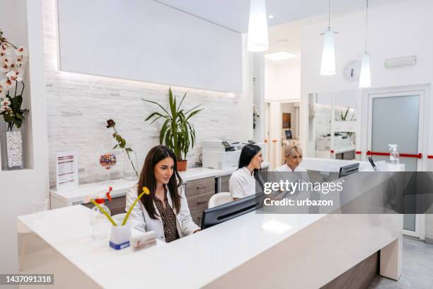 krankenhausrezeptionisten arbeiten hinter der theke - arztpraxis stock-fotos und bilder