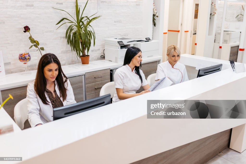 Hospital Receptionists Working Behind The Counter