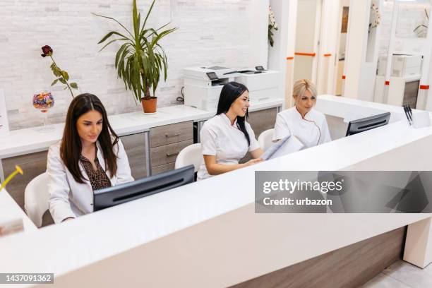 hospital receptionists working behind the counter - reception desk stock pictures, royalty-free photos & images