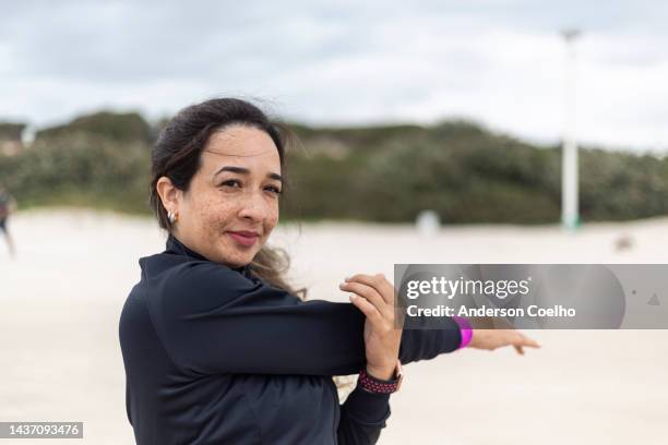 latin woman performing physical exercises on the beach - athlete bulges stock pictures, royalty-free photos & images