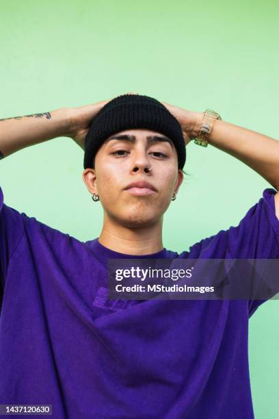 portrait of a young latin man looking at the camera - chapéu roxo imagens e fotografias de stock