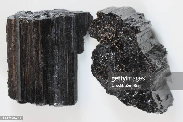 close up of two raw cuts of black tourmaline crystals - tormalina foto e immagini stock