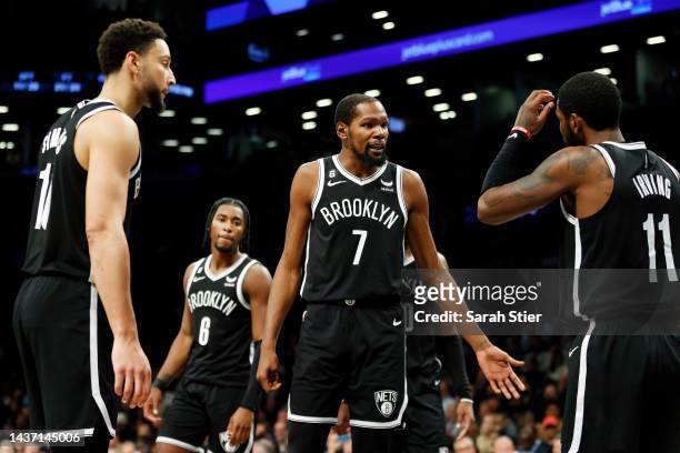 Kevin Durant talks with Ben Simmons and Kyrie Irving of the Brooklyn Nets during the second half against the Dallas Mavericks at Barclays Center on...