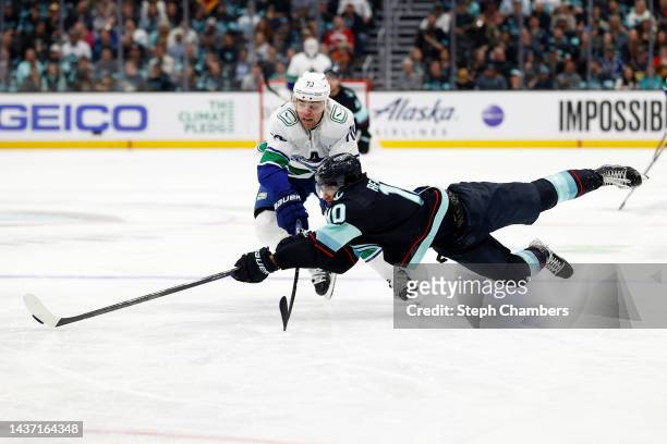 Matty Beniers of the Seattle Kraken dives for the puck against Tanner Pearson of the Vancouver Canucks during the third period at Climate Pledge...