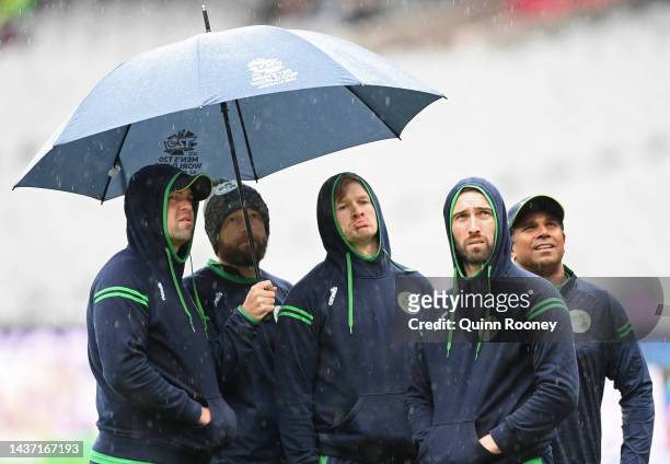 Members of the Irish team watch the rain fall during the ICC Men's T20 World Cup match between Afghanistan and Ireland at Melbourne Cricket Ground on...
