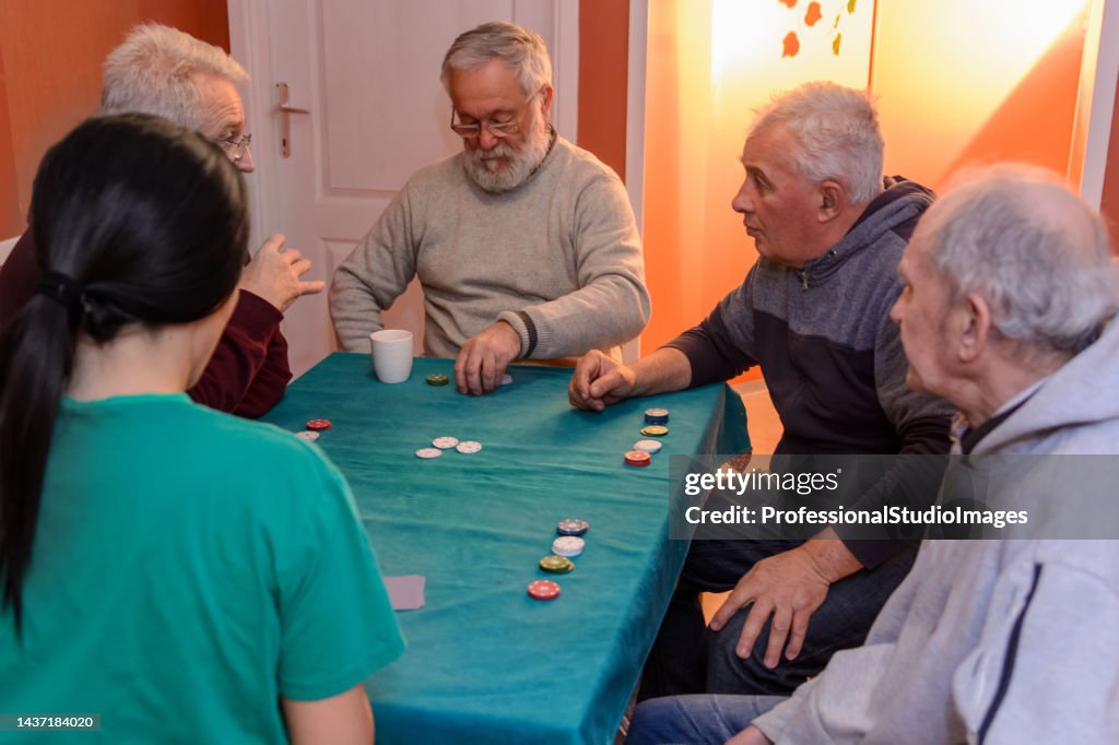 A small group of seniors play cards at home and have a lot of fun.