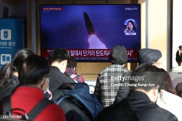 People watch a television broadcast showing a file image of a North Korean missile launch at the Seoul Railway Station on October 28, 2022 in Seoul,...