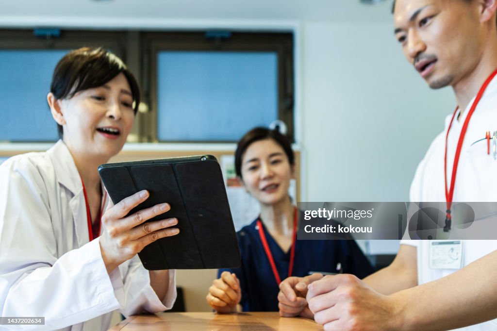 Doctors having a meeting while looking at a tablet.