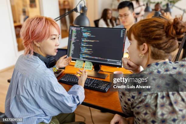 creative businesswomen discuss over new coding program in the office - dyed red hair stock-fotos und bilder