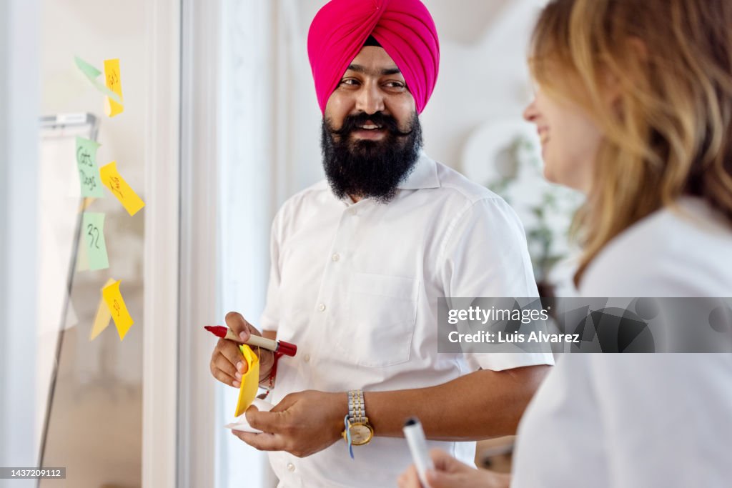 Startup professionals brainstorming with notes on a glass wall in office