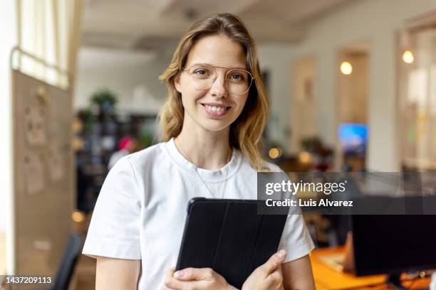 portrait of a happy young businesswoman in office - happy ipad beautiful stockfoto's en -beelden