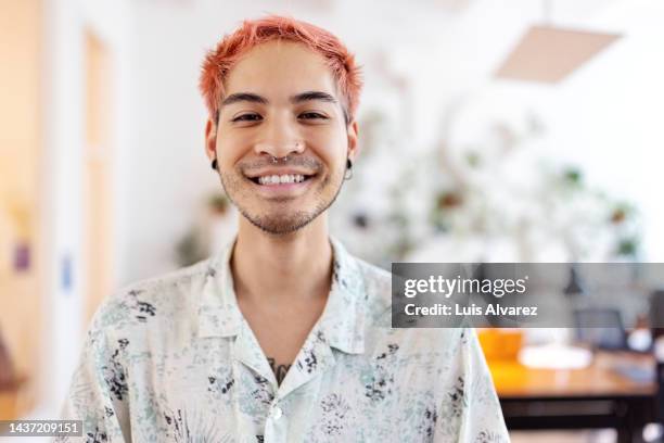 portrait of smiling young asian man at coworking office - haarkleur stockfoto's en -beelden