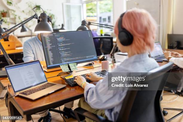 businesswoman wearing a headset coding on computer at coworking office - data scientist stock pictures, royalty-free photos & images