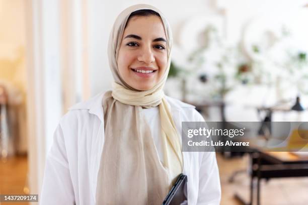 close-up portrait of a confident young middle eastern woman at office - woman hijab stock pictures, royalty-free photos & images