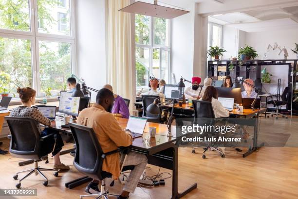 creative business team working in an open plan office - desk office stockfoto's en -beelden
