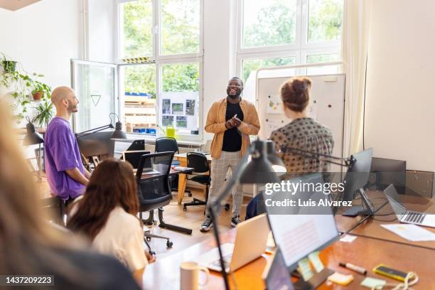 african man giving presentation to startup team at office - marketing kommunikation stock-fotos und bilder