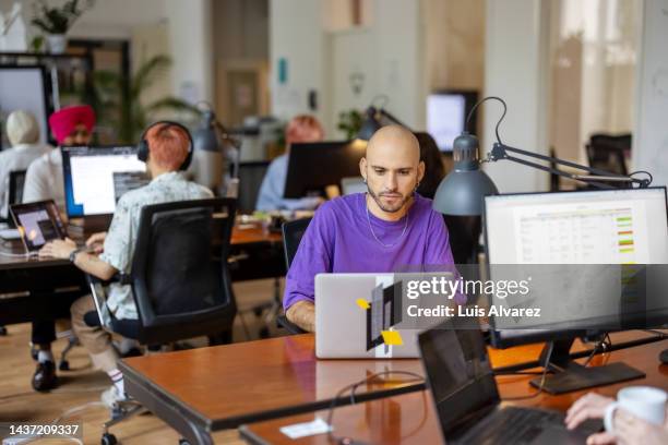 man working on laptop at coworking office - purple shirt fotografías e imágenes de stock