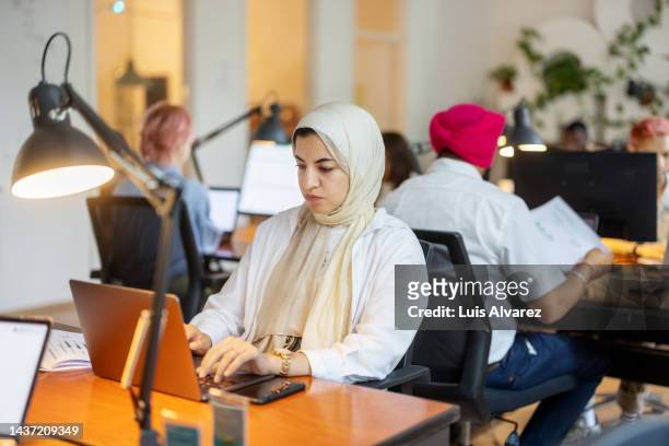 islamic woman working on laptop at a coworking office - foulard foto e immagini stock