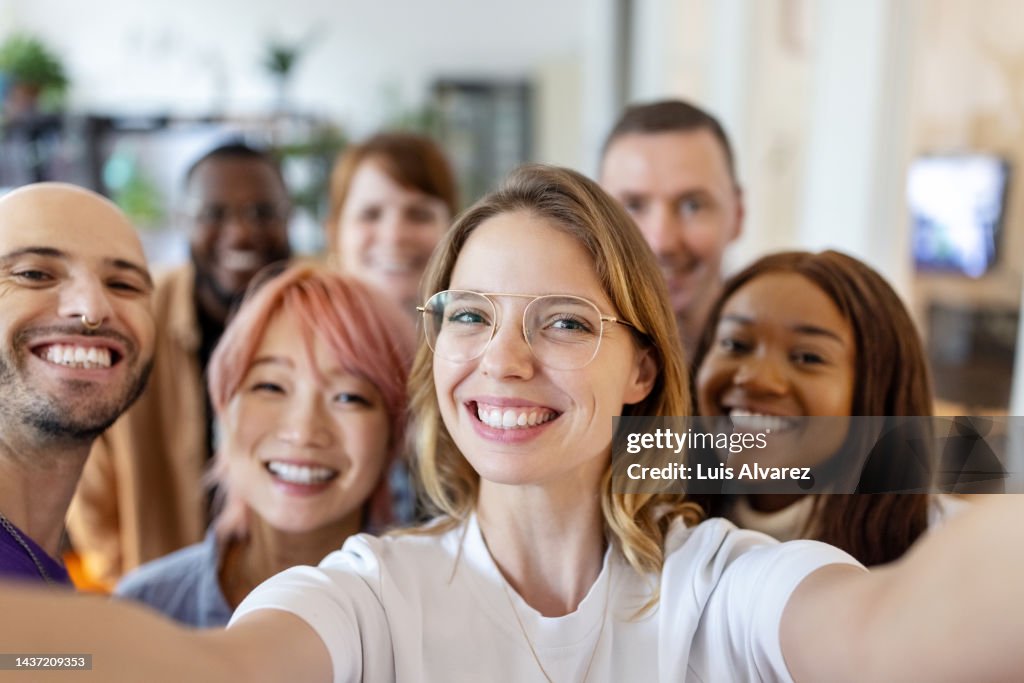 Businesswoman taking selfie with team in office