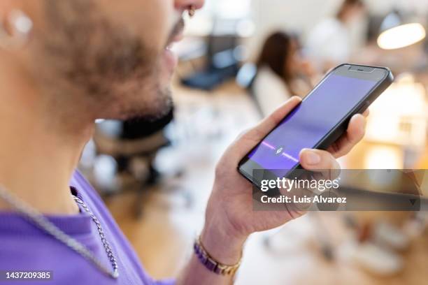 close-up of man recording voice message on cellphone at office - diktera bildbanksfoton och bilder