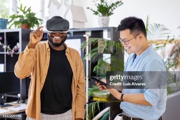 colleagues testing out virtual reality device inside the metaverse - erweiterte realität stock-fotos und bilder