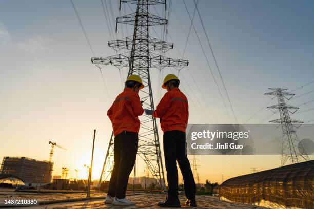 two electric workers using tablet computer at sunset - elnät bildbanksfoton och bilder