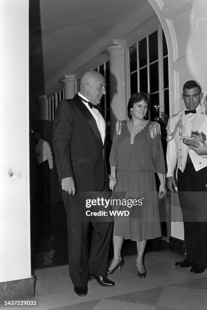 Telly Savalas, Julie Hovland, and a military escort attend an event at the White House in Washington, D.C., on September 10, 1985.