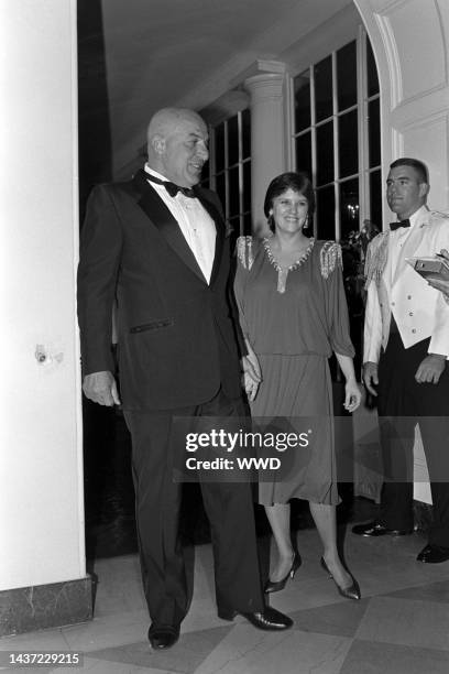 Telly Savalas, Julie Hovland, and a military escort attend an event at the White House in Washington, D.C., on September 10, 1985.