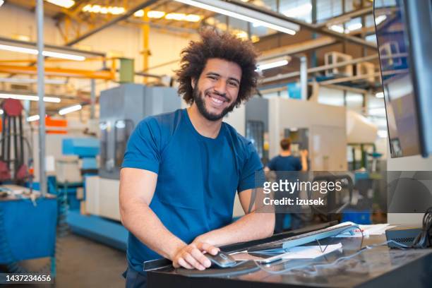 portrait of smiling male engineer with mouse and keyboard at desk in industry - afro man stock pictures, royalty-free photos & images